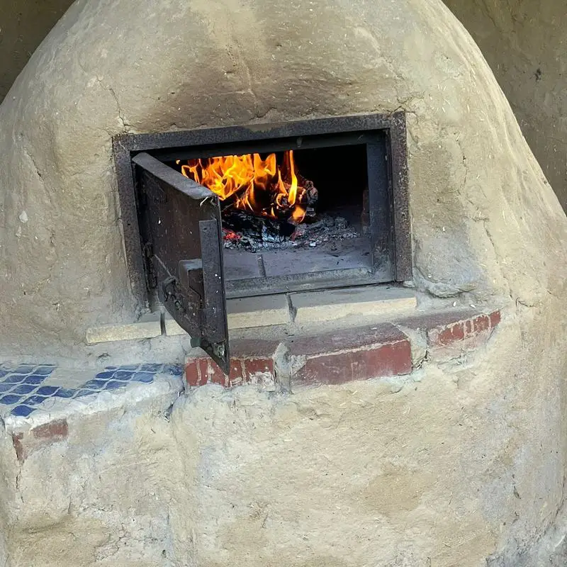 Feuer brennt im gemauerten Lehmbackofen im Garten