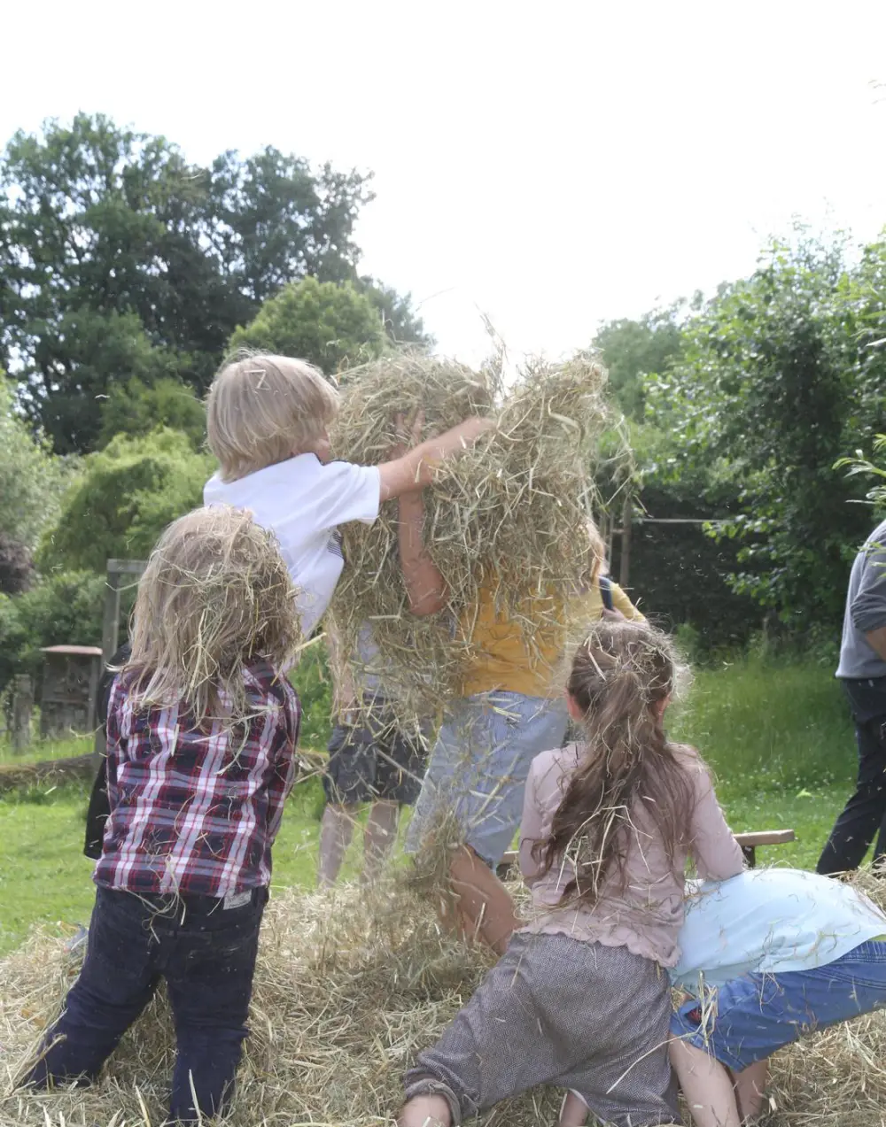 Kinder spielen im Garten des Kinderhauses in einem Haufen Stroh