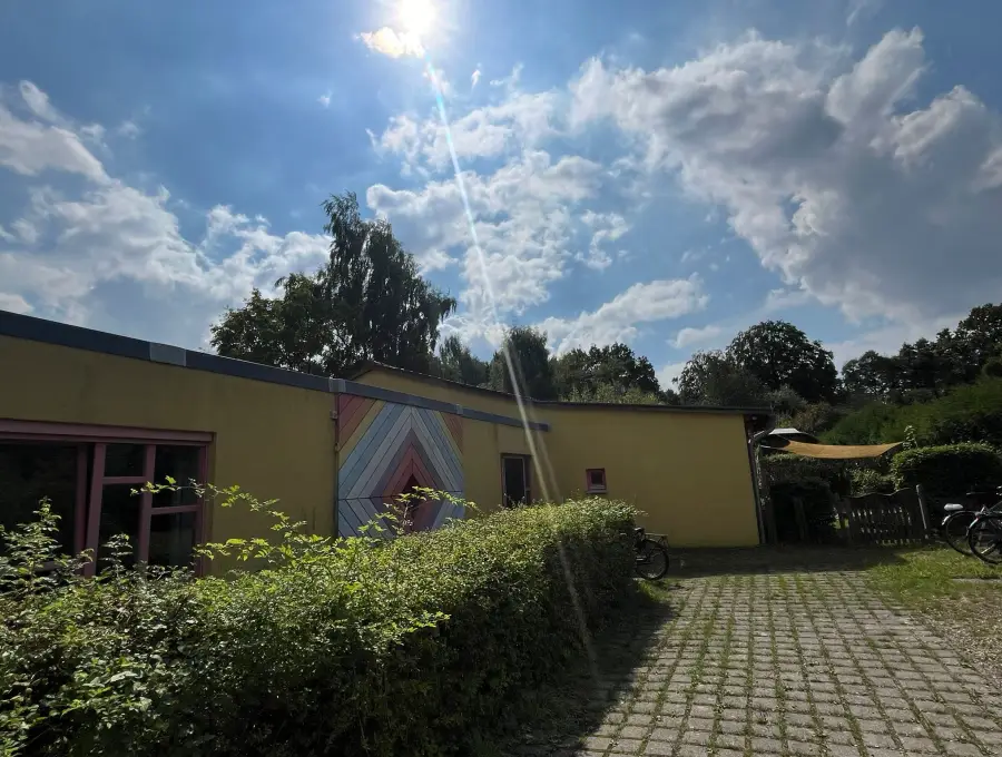Die gelbe Hofseite des Kinderhauses mit einem großen gemalten Zickzack-Bogen in Regenbogenfarben